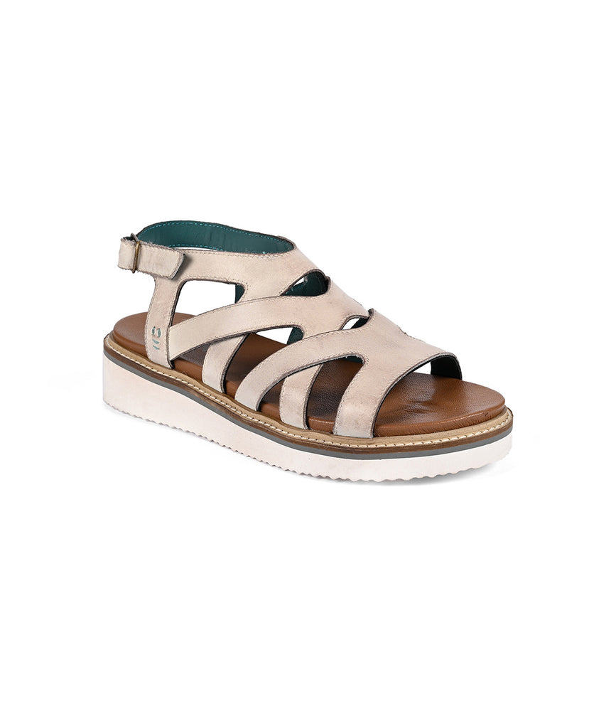 
                  
                    The Roan Centrist sandal features a beige strappy design with a thick white sole, ankle metal buckle closure, and a soft foam outsole for added comfort.
                  
                