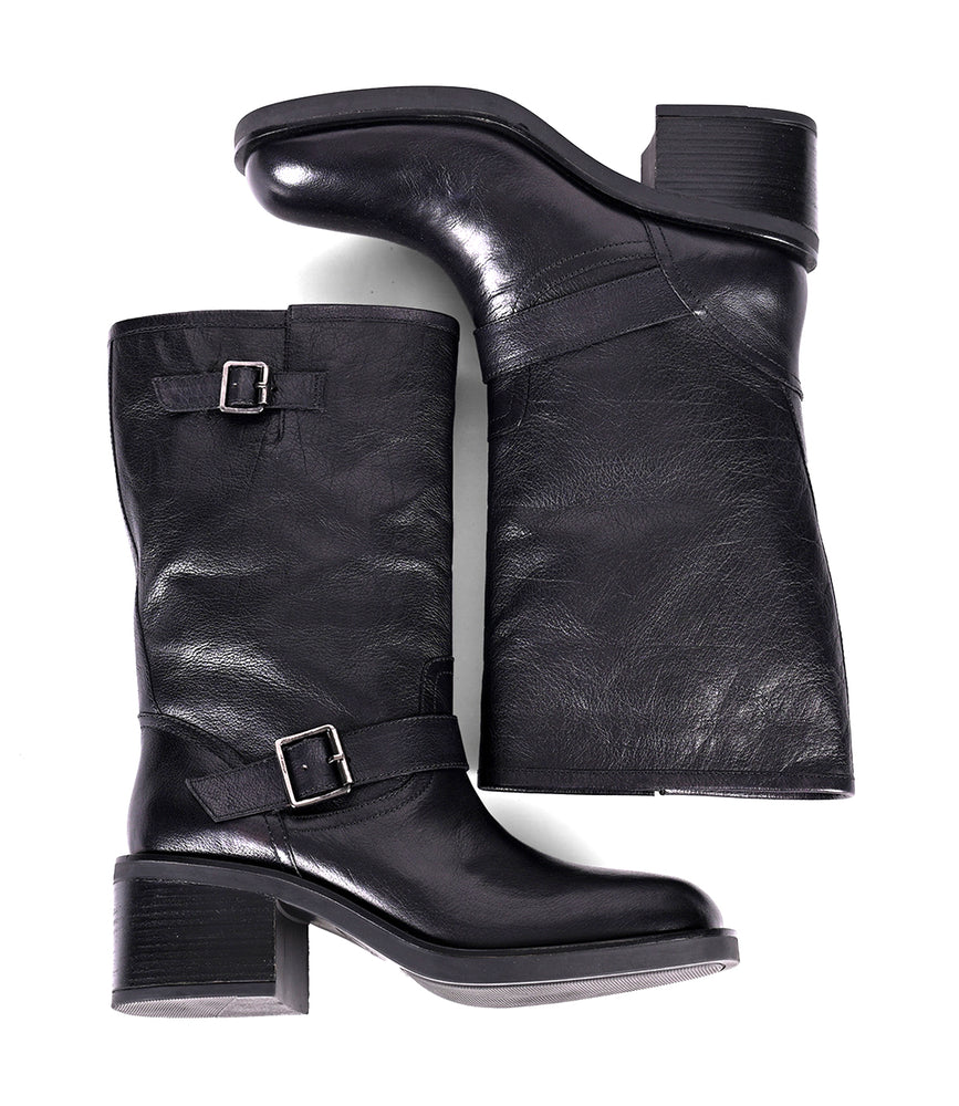 
                  
                    Women's mid-height black leather boots with side buckles, laid side by side
                  
                