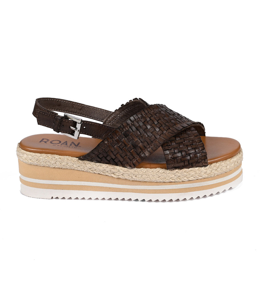 
                  
                    The Roan "Into" sandal features a brown woven platform with a cross-strap design and adjustable ankle strap. Its lightweight serrated foam outsole and rope-detailed platform sole highlight artisanal craftsmanship for an elegant touch.
                  
                