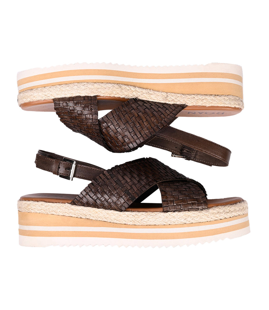 
                  
                    Two Into sandals by Roan, featuring brown woven leather and platform soles, stacked sole to sole, showcasing artisanal craftsmanship.
                  
                