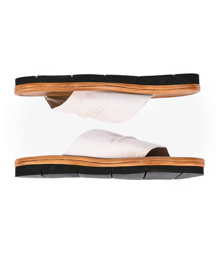 
                  
                    The Roan Nosy slip-on sandals, featuring white uppers, black soles, and tan midsoles, are showcased from the side on a white background and perfectly capture summer style.
                  
                