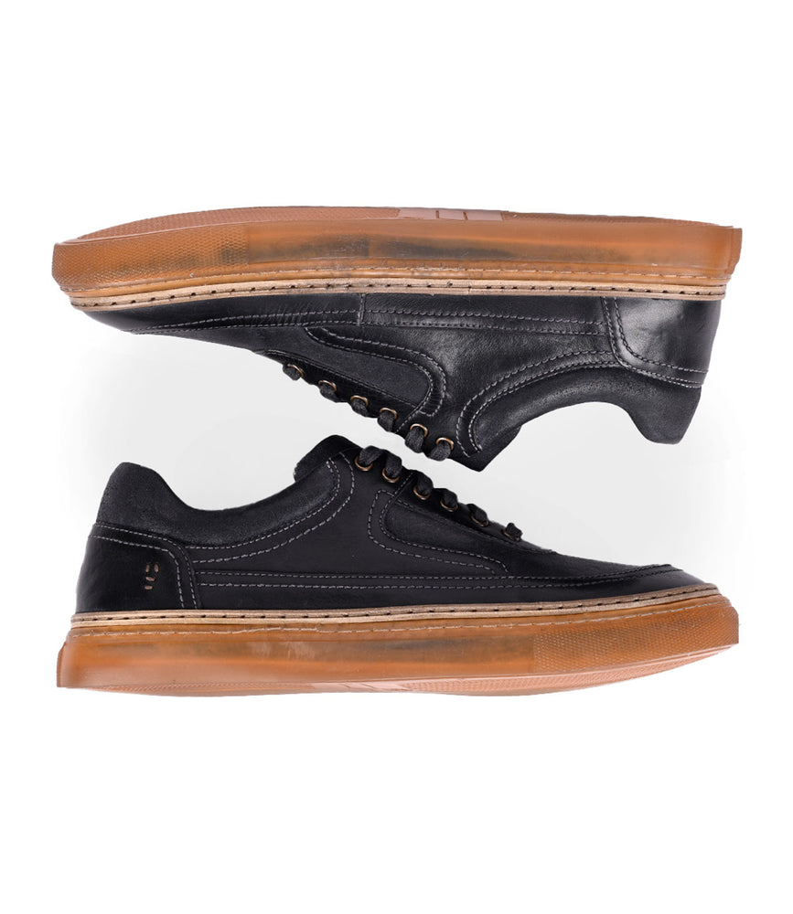 
                  
                    Roan's Eminent sneakers, sleek black lace-ups made from top-grain leather with brown rubber soles, are artfully positioned one above the other against a crisp white background.
                  
                