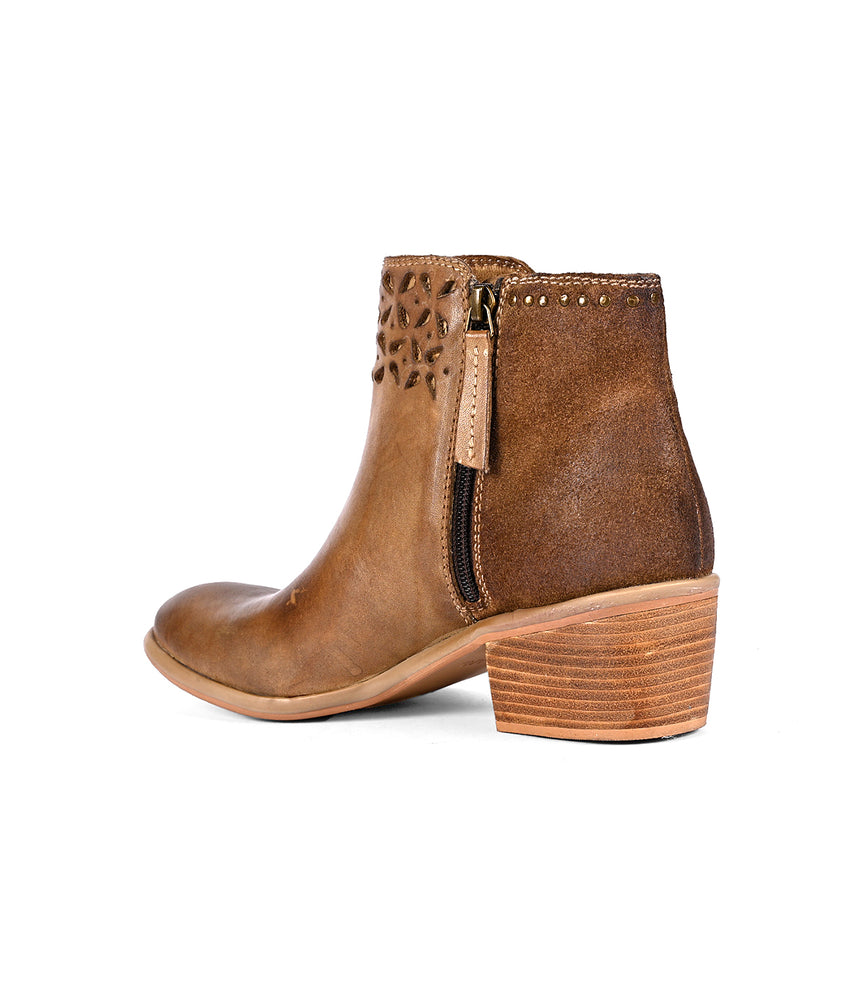 
                  
                    The Liz Cutout by Roan is a brown ankle boot featuring a side zipper, low stacked heel, decorative cutouts at the top, and gold rivet details. It also boasts an intricate cutout petal design that adds a touch of elegance.
                  
                